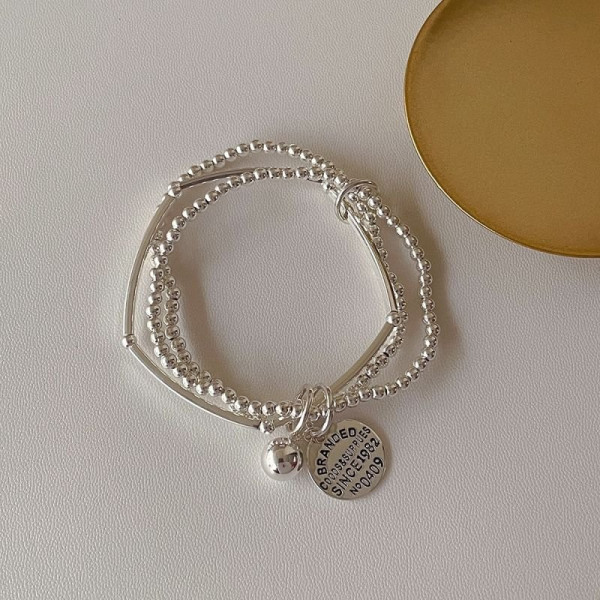 Многослойный браслет из серебристых бусин с жетоном CJE02756