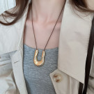 Лариат из темного текстильного шнура с массивной золотистой подвеской-подковой CJN49505